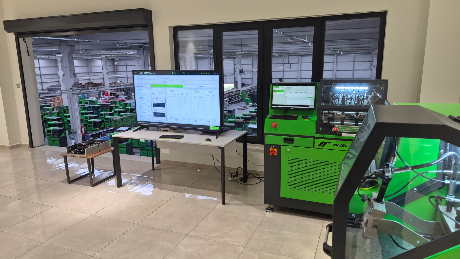 Injectune demonstration area with test benches, a large software display and the production floor beyond the windows.